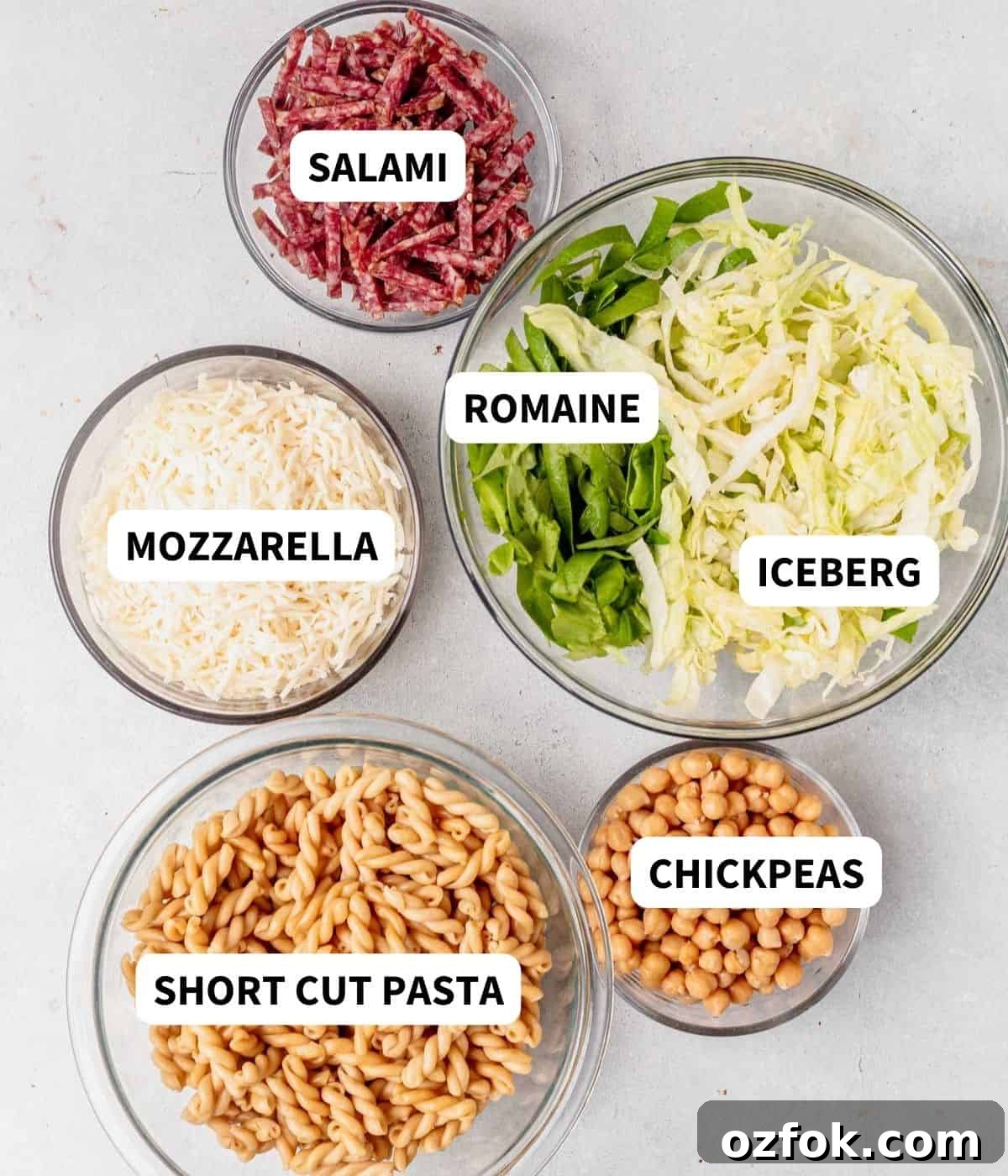 pasta, salami, mozzarella, chickpeas, and lettuce on a countertop