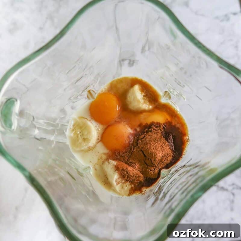 Process shot - bananas, eggs, vanilla, cinnamon, and milk in a blender.