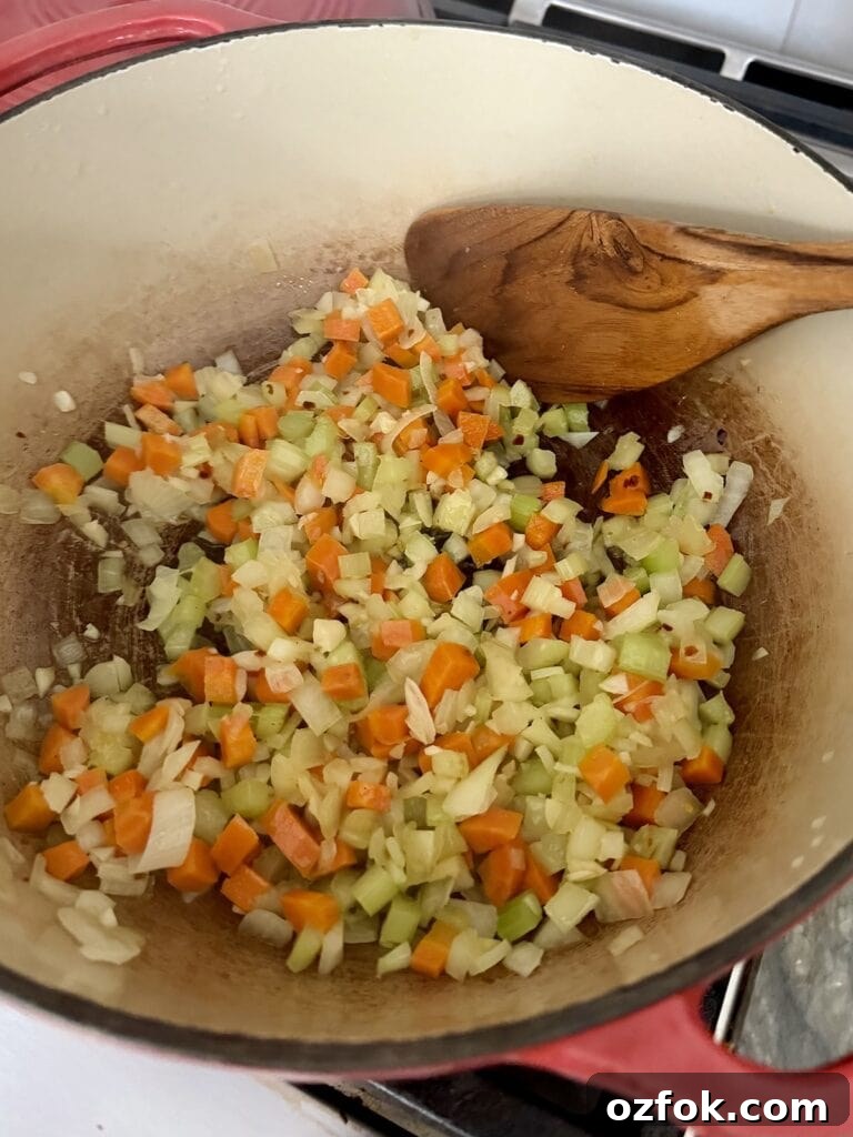 Classic Italian Minestrone Soup Recipe — Hearty Vegetable Stew 7 Sautéing mirepoix in Dutch oven, with wooden spatula.