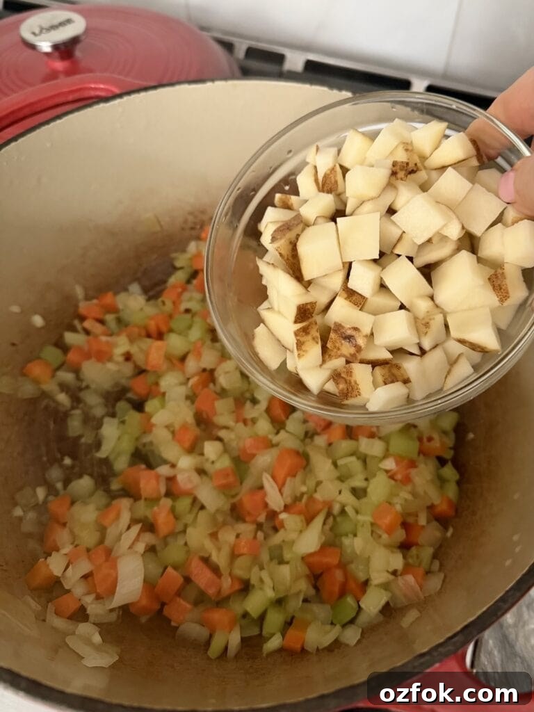 Classic Italian Minestrone Soup Recipe — Hearty Vegetable Stew 8 Adding diced potatoes to mixture in Dutch oven.