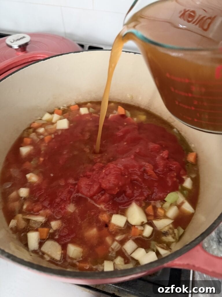 Classic Italian Minestrone Soup Recipe — Hearty Vegetable Stew 9 Pouring broth into pot to make Italian minestrone soup.