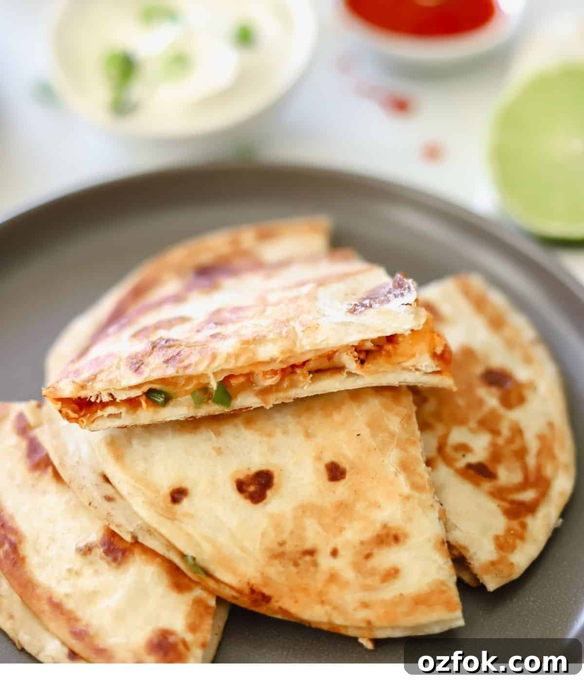 12 Quick Weeknight Dinners Made with Rotisserie Chicken 4 Buffalo chicken quesadilla cut into fours on a gray plate