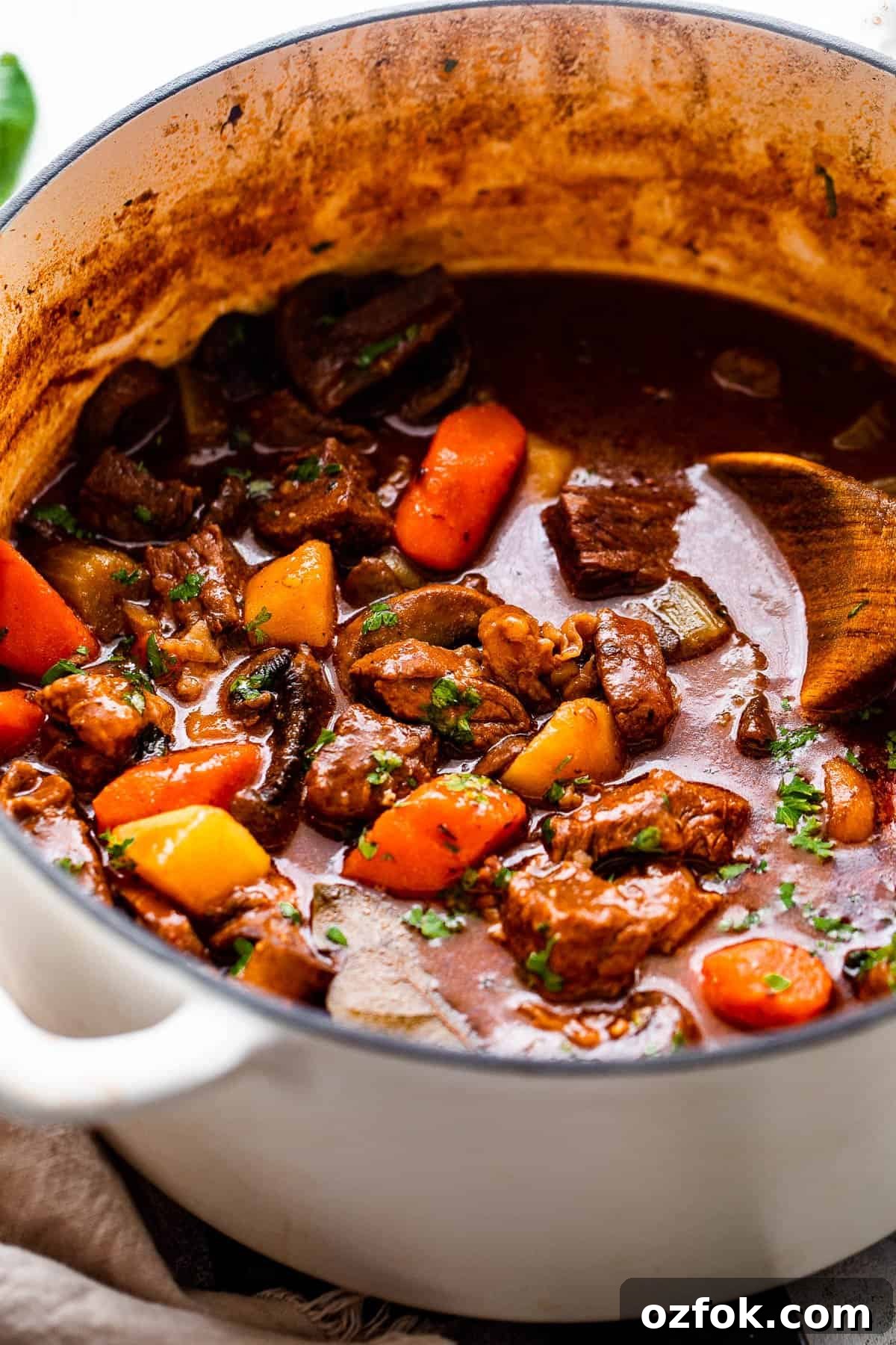 This hearty, Irish inspired Guinness Beef Stew is packed with tender beef, potatoes, carrots, and mushrooms, all cooked in a thick, delicious savory broth. side shot of guinness beef stew studded with chunks of beef and vegetables.