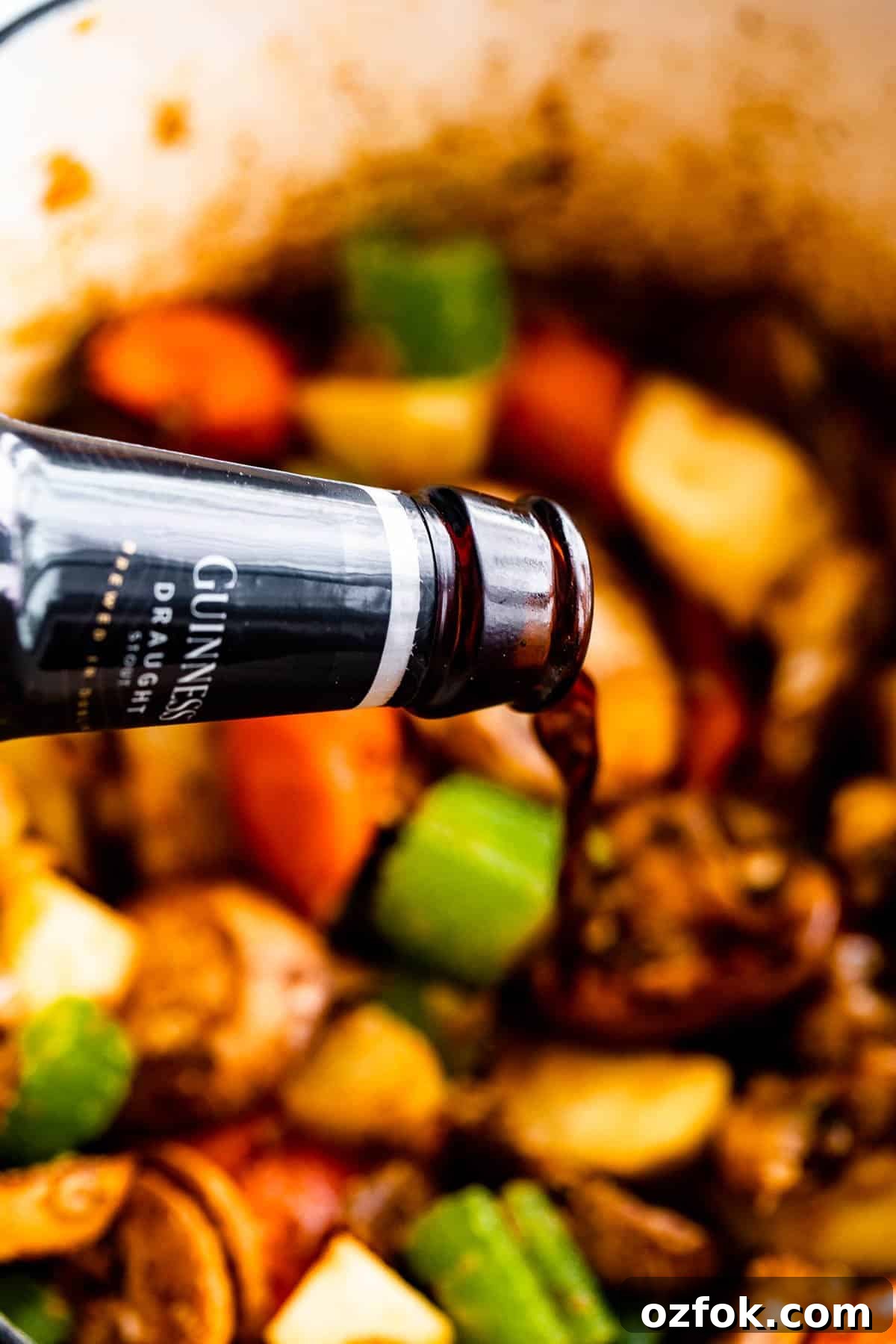 Sauté the veggies. pouring guinness beer over chopped vegetables and beef chunks inside a pot.