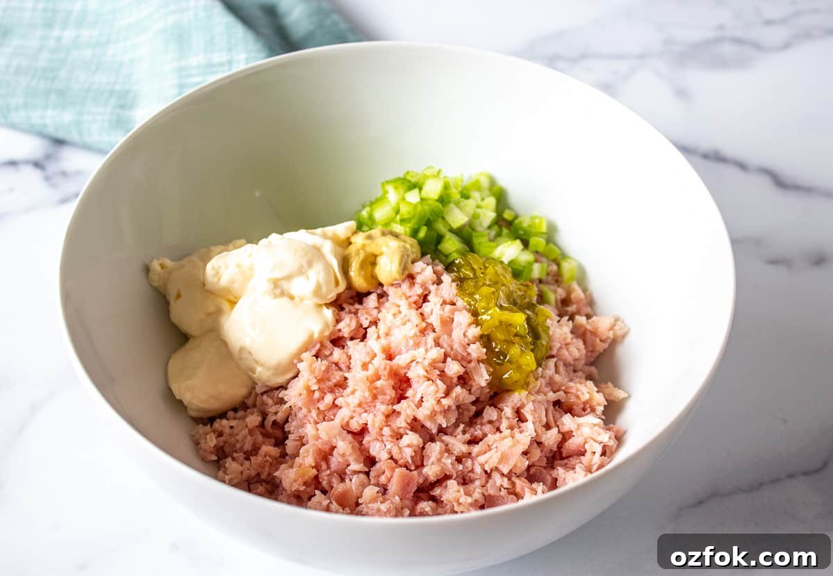 Classic Creamy Ham Salad Recipe for Sandwiches and Dips 3 A white bowl filled with chopped ham, diced celery and mayonnaise.
