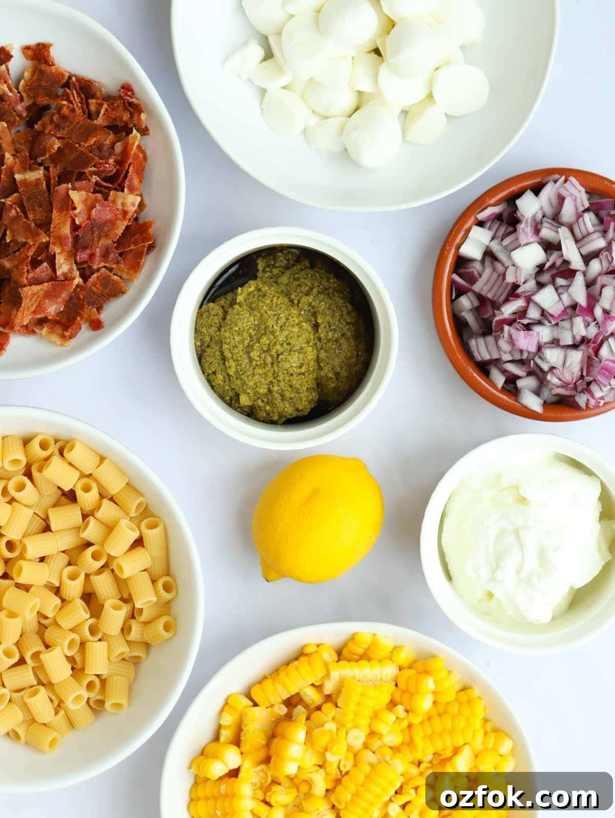 15-Minute Pesto Pasta Salad Recipe for Quick Weeknight Meals 4 Ingredients for a pesto pasta salad recipe laid on a white counter top.