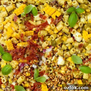 15-Minute Pesto Pasta Salad Recipe for Quick Weeknight Meals 7 A close up of pasta mixed together with lots of ingredients to make a delicious pesto pasta salad.