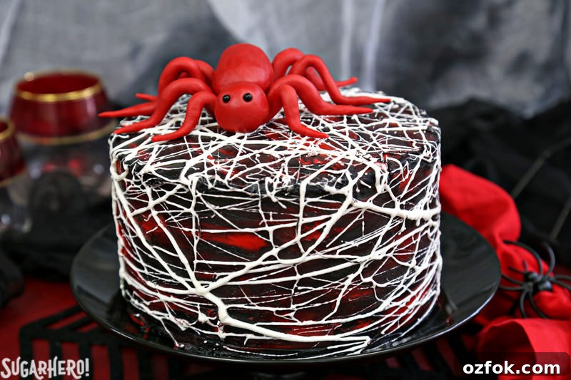 Red Velvet Marshmallow Spiderweb Cake—classic red velvet cake with black chocolate buttercream, covered with a web of marshmallow spiderwebs! Red Velvet Marshmallow Spiderweb Cake with red candy spider on top