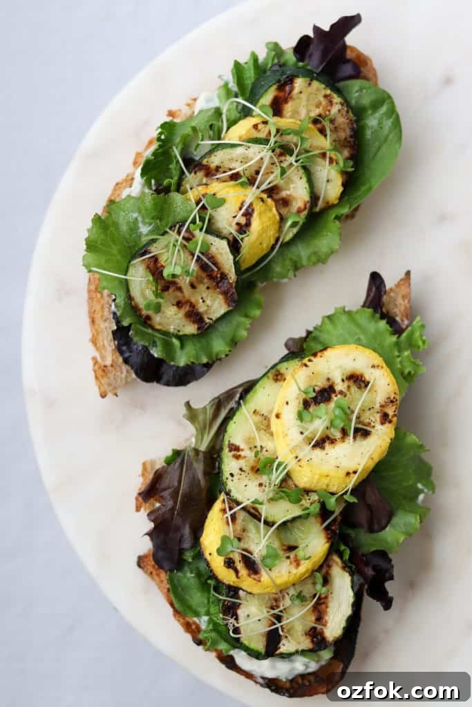 Grilled Summer Squash Smørrebrød with Basil Mayo 2 Open sandwiches topped with lettuce and grilled summer squash on a plate