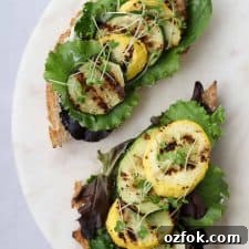 Open sandwiches topped with lettuce and grilled summer squash on a plate
