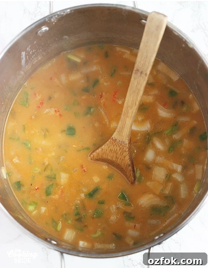 Authentic Cajun Crawfish Pie Recipe: Southern Comfort Dish 4 stirring crawfish filling in a stock pot with a wooden spoon