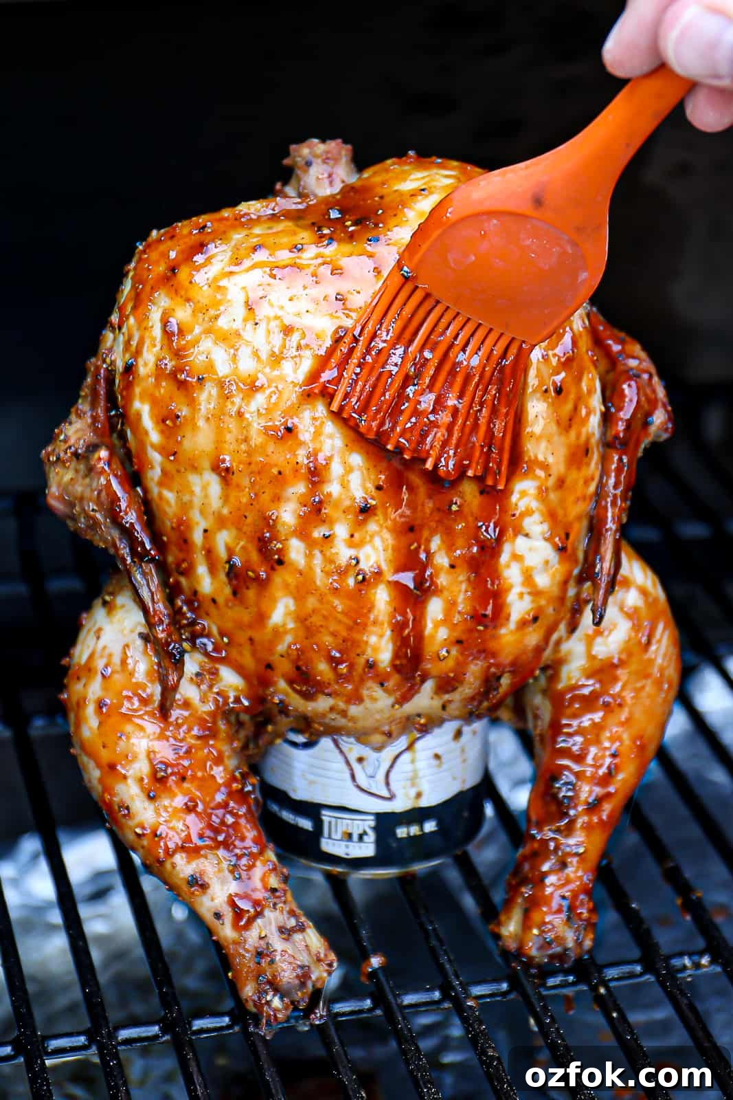 Pellet Smoker Beer-Can Chicken Recipe for Juicy, Crispy Skin 7 Closeup Basting Traeger Smoked Beer Can Chicken With BBQ Sauce While Smoking It