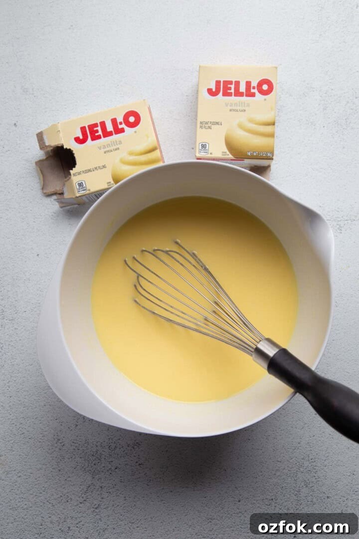 Creamy Twinkie Layer Cake Recipe You’ll Love 5 vanilla pudding in a white bowl with a whisk.