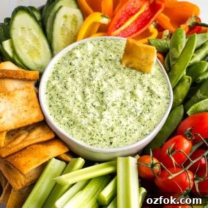 Dairy-Free Tzatziki Sauce: Authentic Vegan Greek Recipe 13 Creamy green dip in a bowl, surrounded by colorful vegetables.