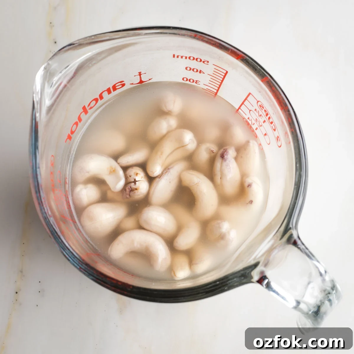 Dairy-Free Tzatziki Sauce: Authentic Vegan Greek Recipe 4 Glass measuring cup with water covering raw cashews.