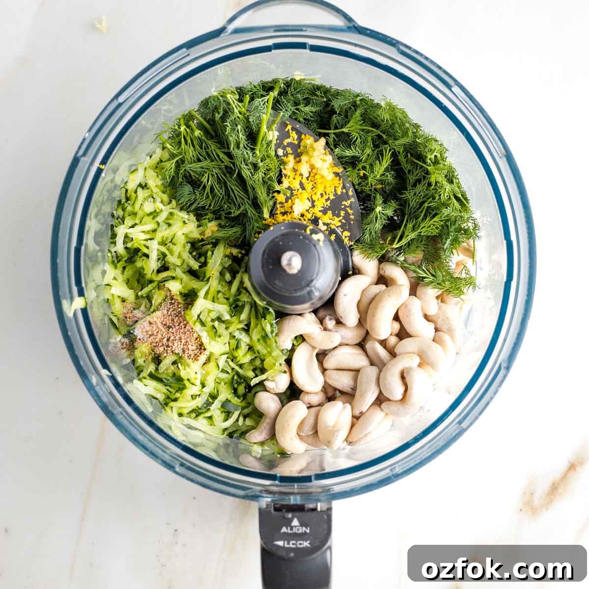 Dairy-Free Tzatziki Sauce: Authentic Vegan Greek Recipe 7 Ingredients for dairy-free tzatziki sauce in the bowl of a food processor: fresh herbs, grated cucumber, cashews, lemon zest and seasonings.