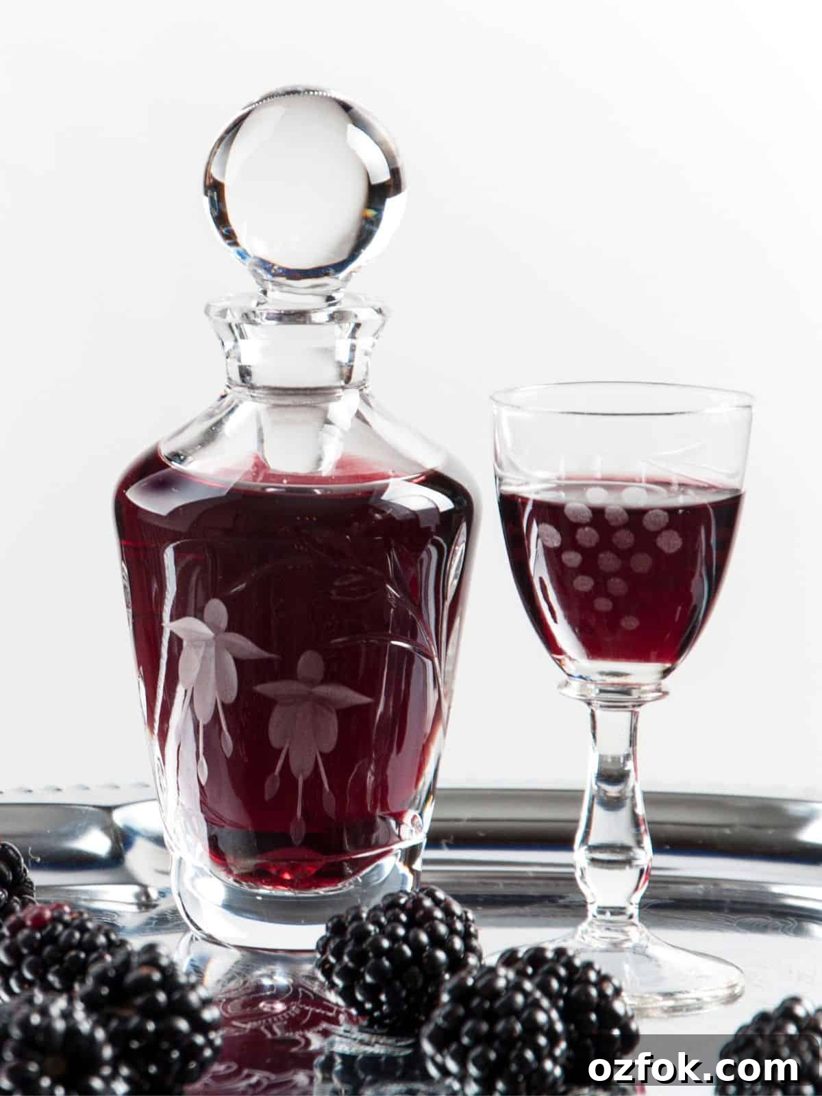 Guide to Cocktail Glasses: Styles, Uses, and Cocktail Pairings 16 A dark red colored cordial in a decanter and glass.