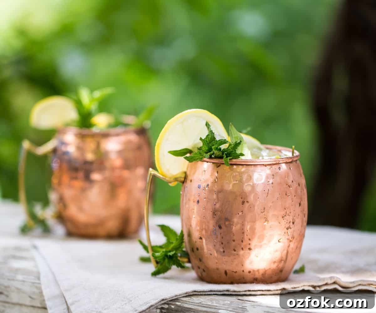 Guide to Cocktail Glasses: Styles, Uses, and Cocktail Pairings 18 A moscow mule on table with lemon wheel and mint.