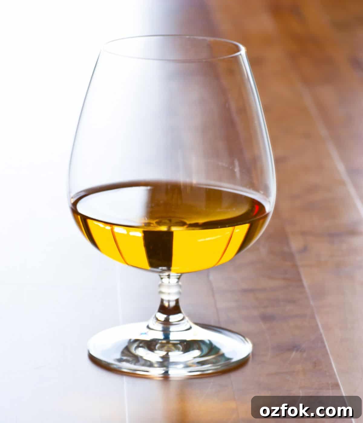 Guide to Cocktail Glasses: Styles, Uses, and Cocktail Pairings 3 Brandy snifter on table with brandy.