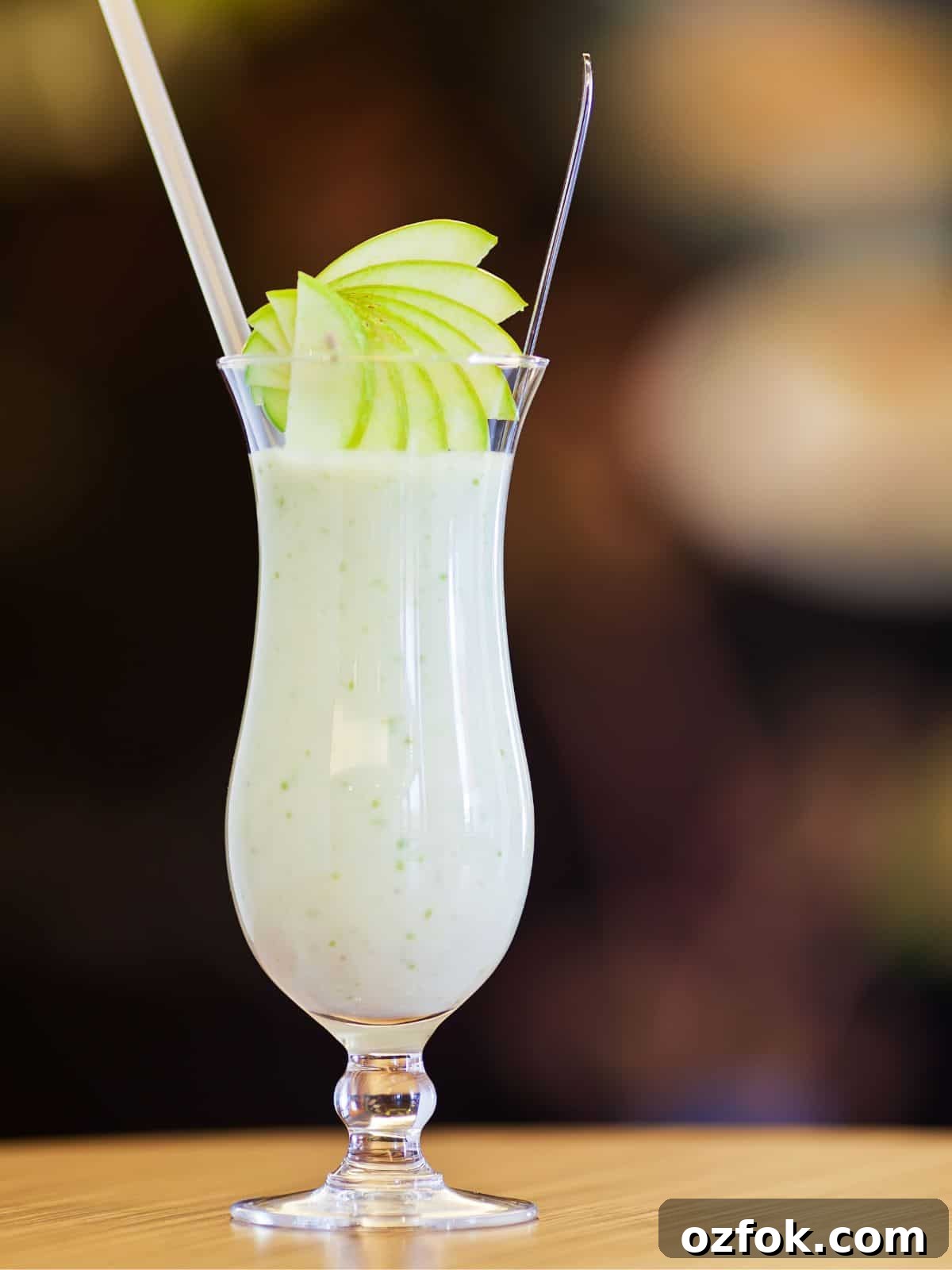 Guide to Cocktail Glasses: Styles, Uses, and Cocktail Pairings 7 A hurricane glass with white cocktail and sliced pears garnish.