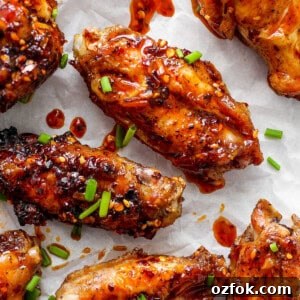 Honey Chili Crisp Grilled Chicken Wings Recipe 12 Glazed chicken wings sprinkled with sesame seeds and chopped green onions on parchment paper.