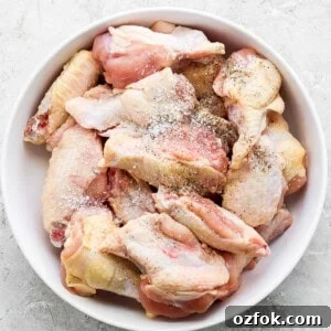 Honey Chili Crisp Grilled Chicken Wings Recipe 8 A bowl of raw chicken wings seasoned with spices.