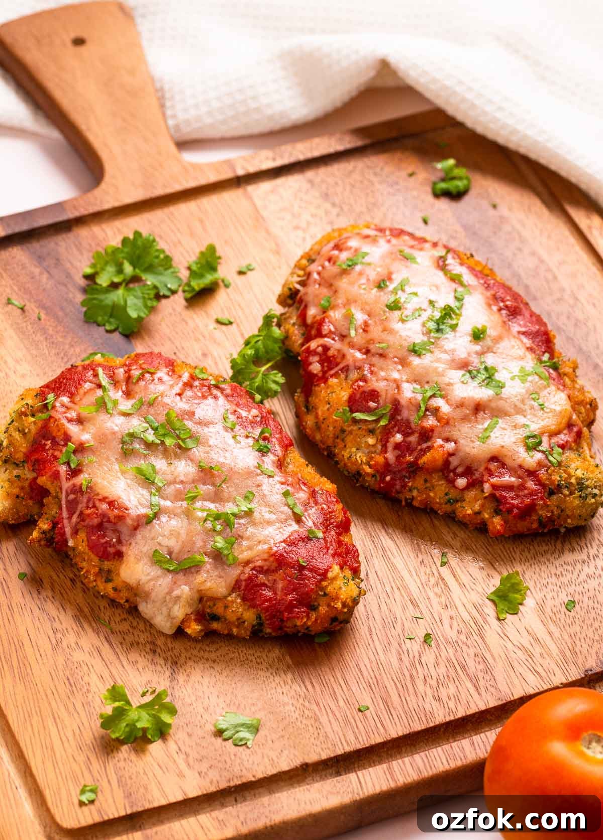 Keto Air Fryer Chicken Parmesan Recipe for Crispy Low-Carb Dinner 2 Two low carb breaded and air-fried chicken parmesan cutlets with marinara sauce and cheese.