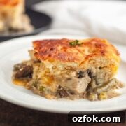 A slice of a chicken pot pie with a bacon biscuit crust.