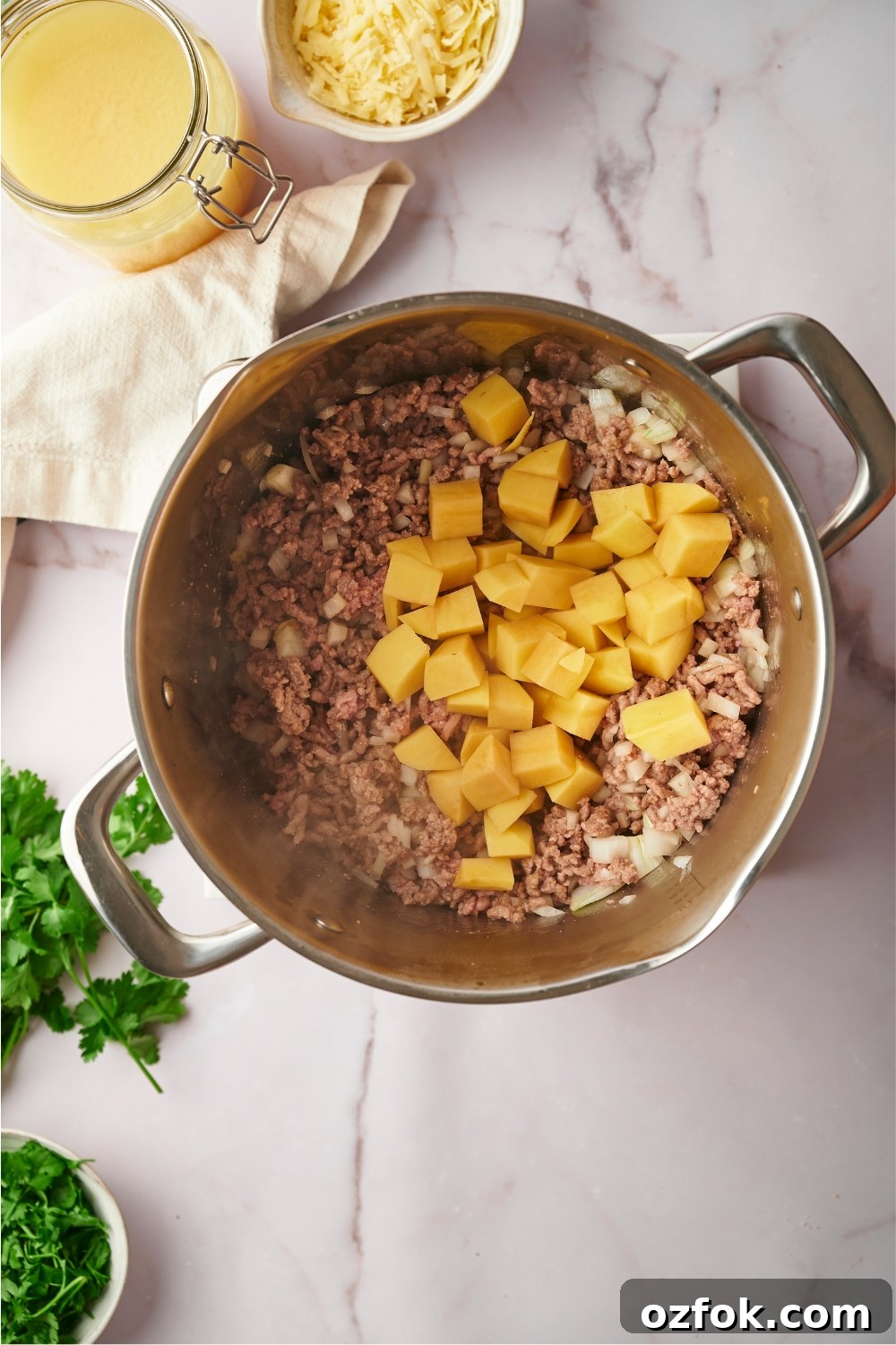 30-Minute Ground Beef and Vegetable Soup Recipe 7 Cubed potatoes on top of ground beef and onions cooking in a pot.