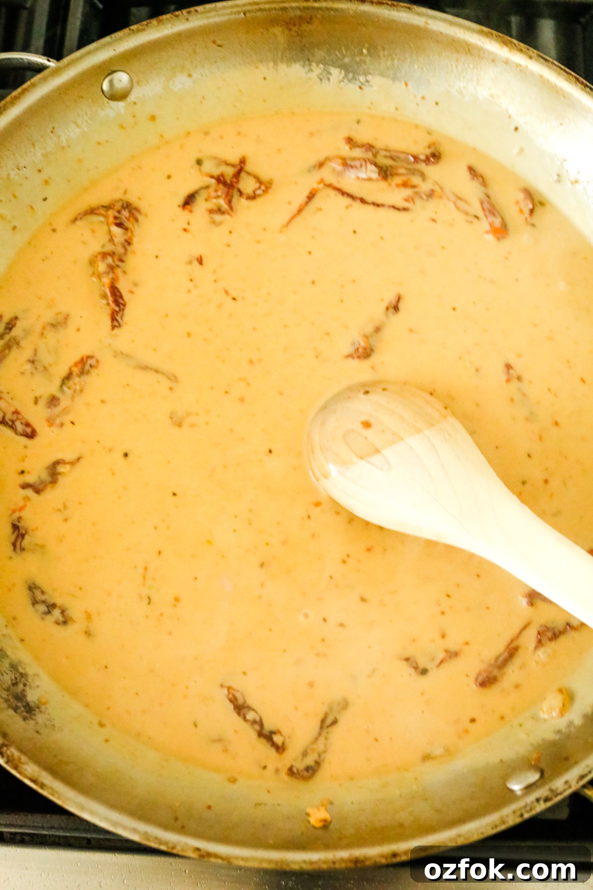 Tuscan-Style Dairy-Free Chicken with Sun-Dried Tomatoes and Herbs 6 stirring sauce with tomatoes