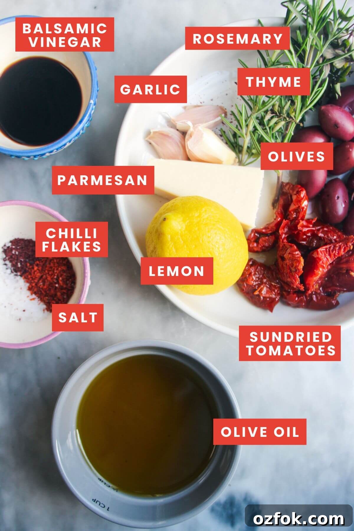 10-Minute Mediterranean Bread Dipping Oil Recipe 3 Ingredients for loaded olive oil dip laid out on a grey marble background and labelled.
