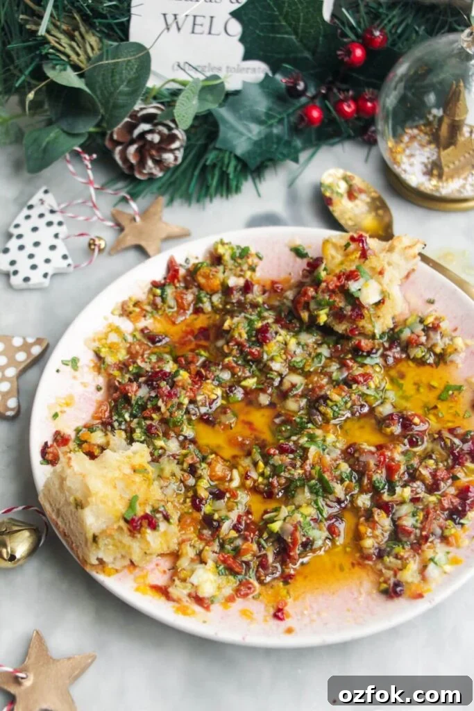 10-Minute Mediterranean Bread Dipping Oil Recipe 6 Festive dipping oil in a small pink plate on a grey surface.