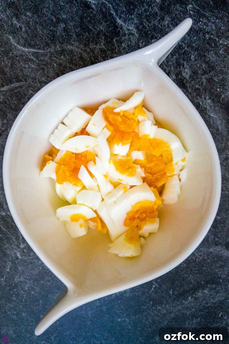 Creamy Classic Egg Salad Recipe for Sandwiches and Lunch 4 Egg quartered in white bowl.