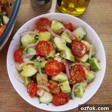 mediterranean cucumber tomato salad with feta in a white colored bowl.