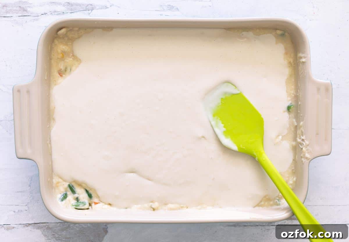 Pyrex pan of pot pie ingredients topped with batter for the crust.