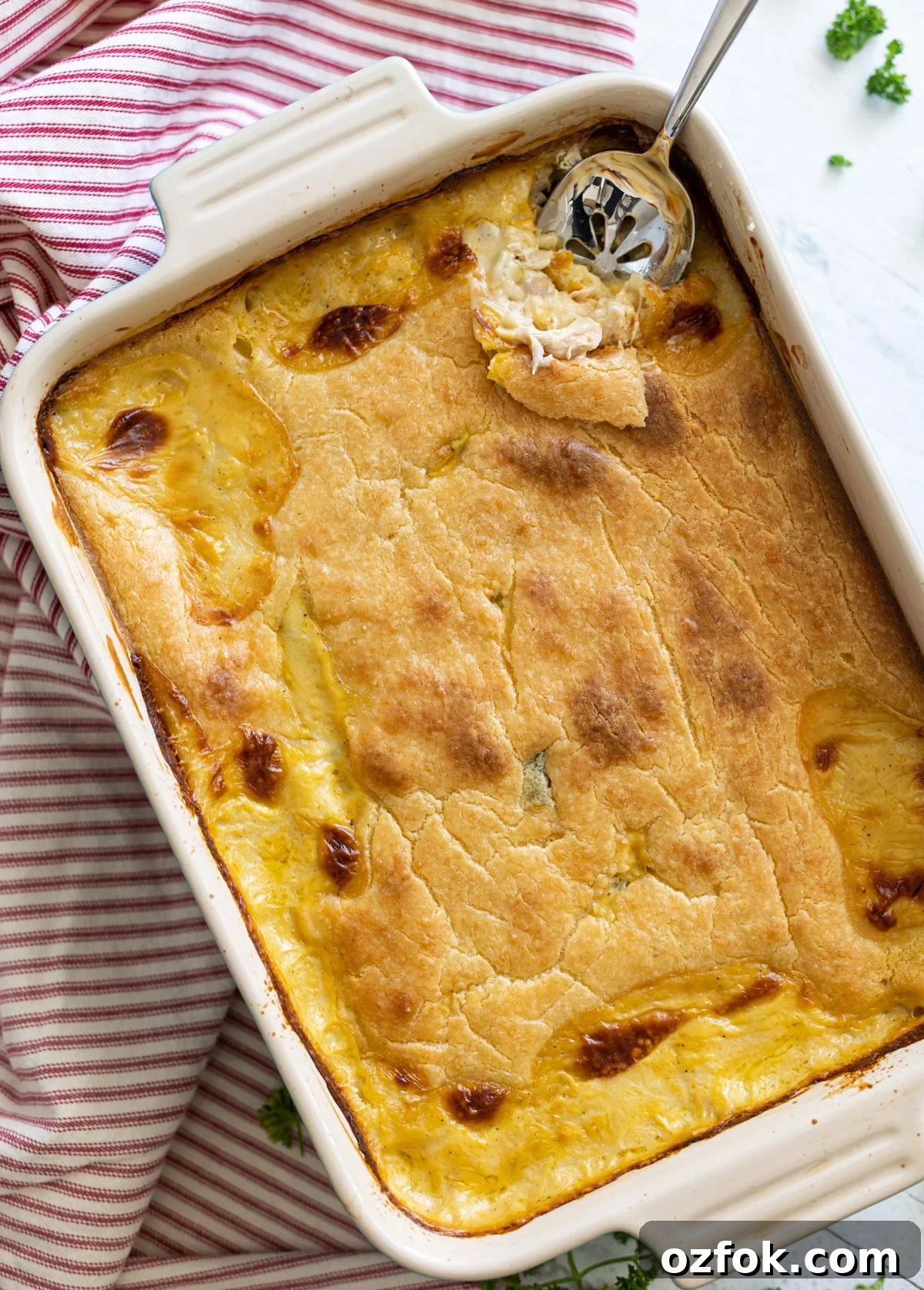 Chicken casserole on table in dish, spoon in dish.