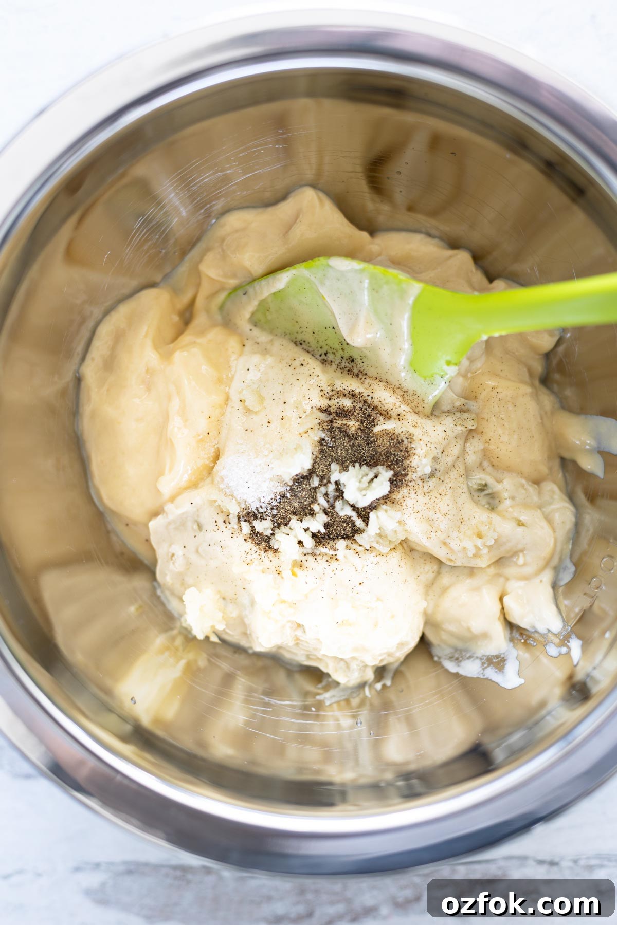Silver mixing bowl of chicken pot pie sauce ingredients prior to stirring.