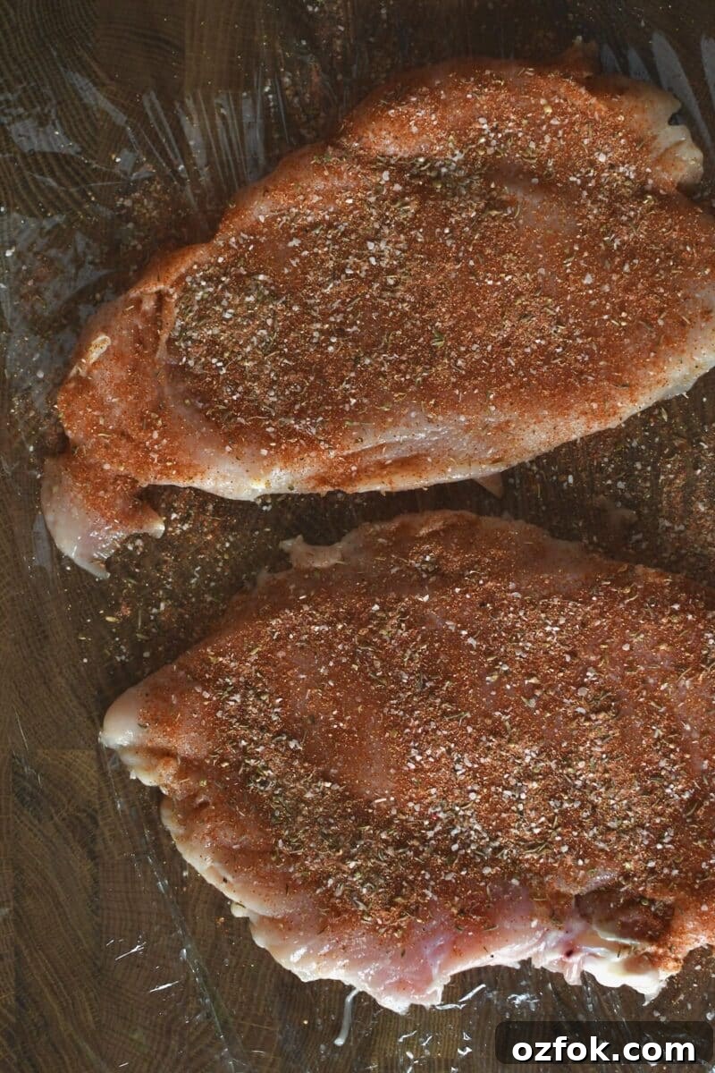 Seasoning the tenderized chicken breasts with cajun seasoning.