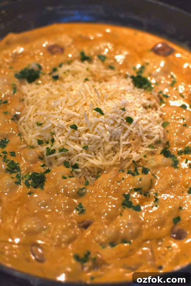 Adding the parmesan cheese and a pinch of parsley to the pan before the pasta.