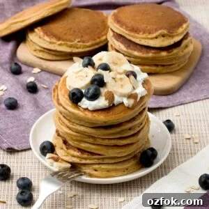 A stack of gluten-free protein pancakes with Greek yogurt blueberries and bananas on top.