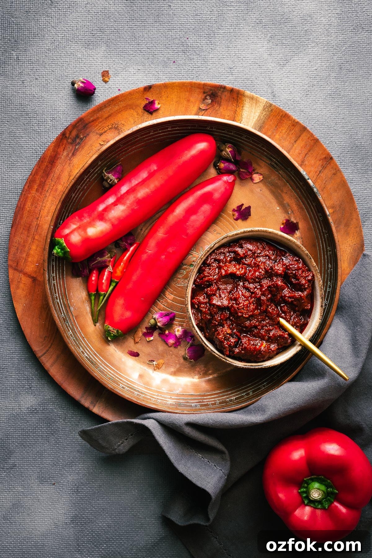 Homemade Rose Harissa Paste Recipe for Vibrant Flavor 2 A bowl of rose harissa paste arranged with fresh red peppers and rose petals.