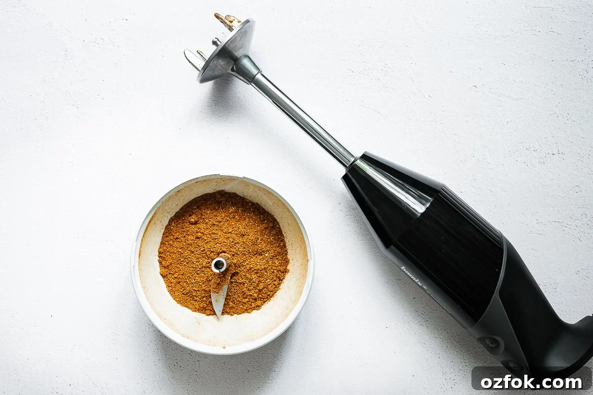 Homemade Rose Harissa Paste Recipe for Vibrant Flavor 6 Chinese five-spice powder in a small food processor attachment next to an immersion blender viewed from above.