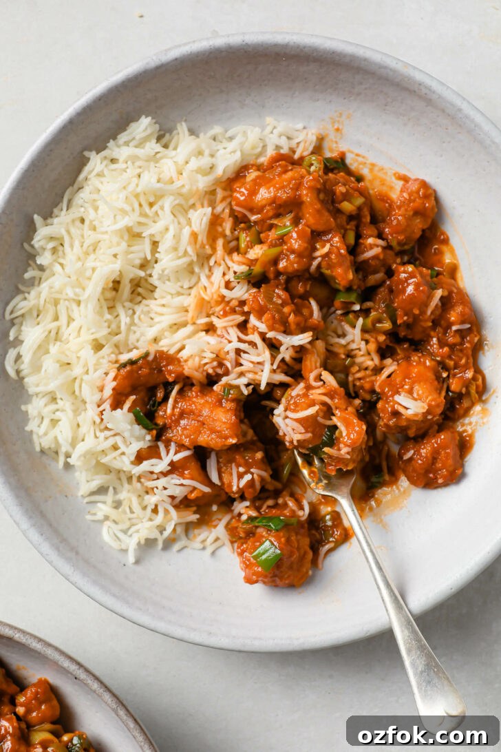 Crispy Chicken Manchurian with Tangy Gravy 11 Partially eaten Chicken Manchurian with rice and a fork.