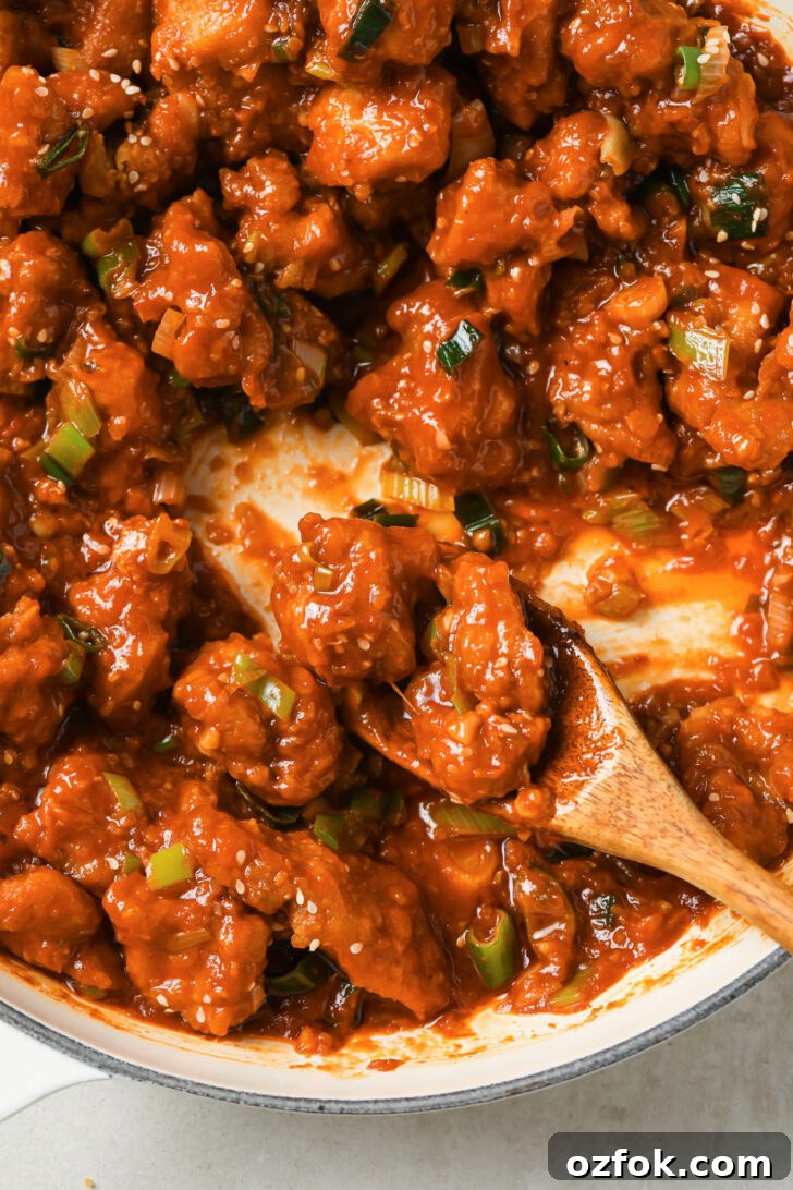 Crispy Chicken Manchurian with Tangy Gravy 4 Close up of Chicken Manchurian in pot with a wooden spoon.