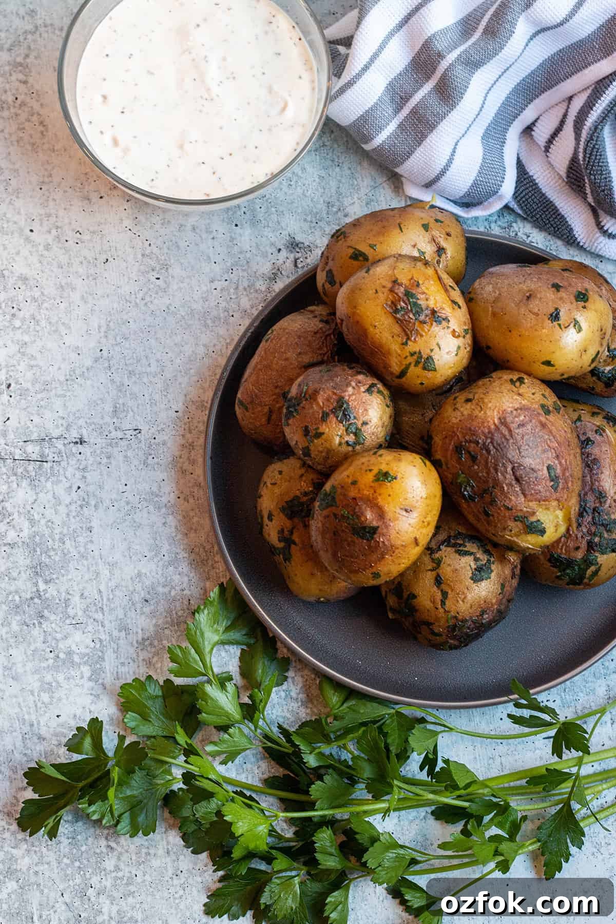 A pile of cook yukon gold potatoes with a bowl of garlic aoili.