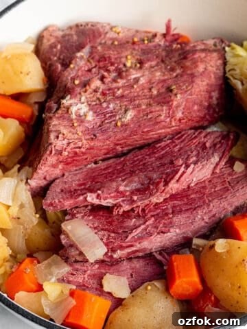 A Dutch Oven pot with a corned beef brisket, cabbage wedge, potatoes and carrots.