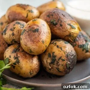 A plate with a stack of Yukon gold potatoes covered in herbs.