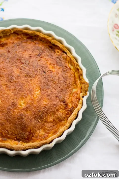 Grandma’s Incredible Ham and Cheese Quiche Recipe 4 Gran's ham and cheese quiche in a white baking dish on a green plate.