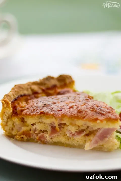 Grandma’s Incredible Ham and Cheese Quiche Recipe 5 A slice of Gran's ham and cheese quiche and a side salad on a white plate.
