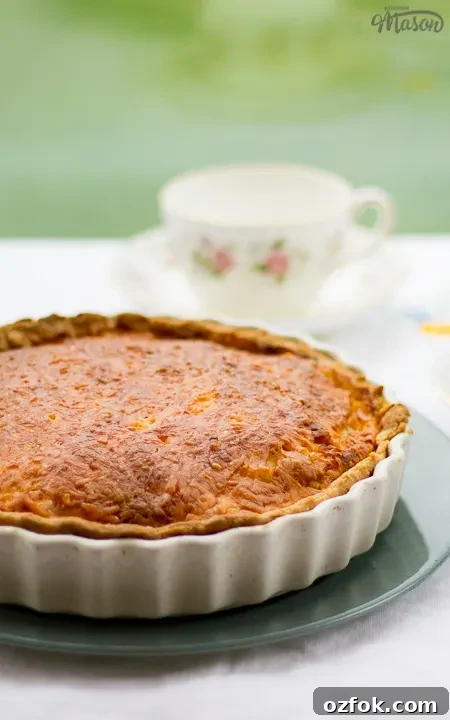 Grandma’s Incredible Ham and Cheese Quiche Recipe 7 Gran's ham and cheese quiche in a white baking dish on a green plate.